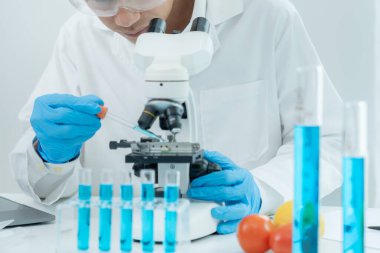 Bilimadamı ileri bilimsel laboratuvarda biyokimyasal örnekleri analiz ediyor. Tıbbi profesyonel kullanım mikroskobu virüsün mikrobiyolojik gelişimini gösteriyor. Fen laboratuvarında biyoteknoloji araştırması.