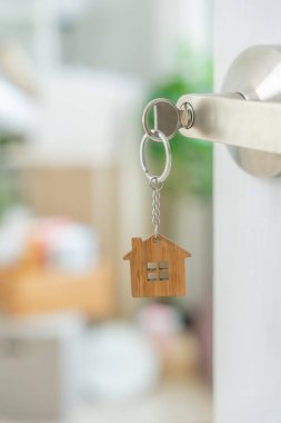 Moving house, relocation. The key was inserted into the door of the new house, inside the room was a cardboard box containing personal belongings and furniture. move in the apartment or condominium