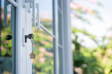 Landlord key for unlocking house is plugged into the door. Second hand house for rent and sale. keychain is blowing in the wind. mortgage for new home, buy, sell, renovate, investment, owner, estate