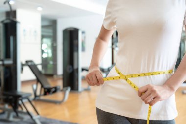 Diyet ve diyet. Güzel, ince kadın vücut ölçüsü fitness için şerit kullanır. Spor elbiseli bir kadın sağlıklı yaşam için kilo verme hedefine, zayıflığa, ince belliye, beslenme uzmanına ulaşır.