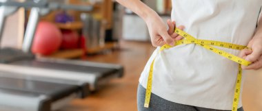 Diyet ve diyet. Güzel, ince kadın vücut ölçüsü fitness için şerit kullanır. Spor elbiseli bir kadın sağlıklı yaşam için kilo verme hedefine, zayıflığa, ince belliye, beslenme uzmanına ulaşır.