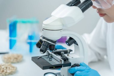 Bilimadamı ileri bilimsel laboratuvarda biyokimyasal örnekleri analiz ediyor. Tıbbi profesyonel kullanım mikroskobu virüsün mikrobiyolojik gelişimini gösteriyor. Fen laboratuvarında biyoteknoloji araştırması.