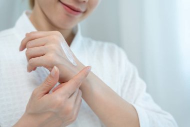 Güzel Asyalı kadın gülümsüyor, cilt kremi kullanıyor. Sağlıklı bir kadın vücuduna krem sürer. Cilt kremi reklamı, kırışıklık önleyici, bebek yüzü, beyazlatma, nemlendirici, gözenekleri sıkma seru