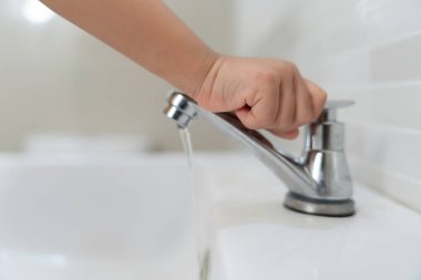 Su tasarrufu. Küçük çocuk çevreyi korumak için tuvaletteki suyu kapatıp duruyor. Yeşillenen gezegen, küresel ısınmayı azalt Dünya 'yı, yaşamı, geleceği, risk enerjisini, krizi, su gününü kurtar