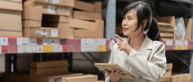 Asyalı kadın işyeri sahibi dijital tablet kullanıyor dağıtım deposu fabrikasındaki stok ürün envanterini kontrol ediyor. Lojistik iş gemisi ve teslimatı, envanter akışı, profesyonel iş akışı.