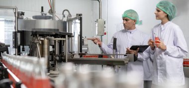 Kalite denetleyicisi, yiyecek veya içecek teknisyeni, müşteriye ürün göndermeden önce durum kontrolü gıda ve içeceklerle ilgili teftiş yapıyor. Üretim lideri makine ve verimliliği yeniden kontrol ediyor