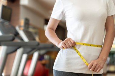 Diyet ve diyet. Güzel, ince kadın vücut ölçüsü fitness için şerit kullanır. Spor elbiseli bir kadın sağlıklı yaşam için kilo verme hedefine, zayıflığa, ince belliye, beslenme uzmanına ulaşır..