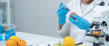 Bilimadamı laboratuvardaki kimyasal gıda kalıntılarını kontrol ediyor. Denetim uzmanları meyvelerin kalitesini incelerler, bilim adamları deneyler, tehlikeler, yasaklanmış maddeler ve kirlilik için elmalara kimyasal madde enjekte ederler.