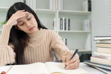 Asyalı kadın öğrencilerin sınavlar yüzünden endişeleri var. Kadınlar kütüphanede sınav ve öğrenme derslerine hazırlanıyor. Stres, umutsuzluk, acele, yanlış anlama okuma, umutsuzluk, beklenti, bilgi