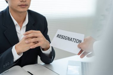 Stresli iş adamları şirketten istifa edecek. Yöneticinin istifa belgesi üzerinde çalışan bir erkek. İstifa, iş bulma ve boşluklar kavramı, kariyer sorunu, sorunlu yaşam