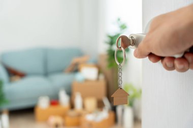 Moving house, relocation. The key was inserted into the door of the new house, inside the room was a cardboard box containing personal belongings and furniture. move in the apartment or condominium