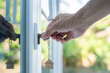 Evin kilidini açmak için ev sahibi anahtarı kapıya takılı. Kira ve satış için ikinci el ev. Sahibi el ile yeni ev için kapı ipoteğini açar, satın alır, satar, yeniler, yatırım, sahip, estat