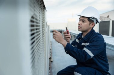 Asian maintenance engineer work on the roof of factory. contractor inspect compressor system and plans installation of air condition systems in construction. technology, walky talky, maintenance