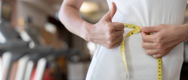 Diyet ve diyet. Güzel, ince kadın vücut ölçüsü fitness için şerit kullanır. Spor elbiseli bir kadın sağlıklı yaşam için kilo verme hedefine, zayıflığa, ince belliye, beslenme uzmanına ulaşır..