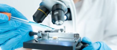 Bilimadamı ileri bilimsel laboratuvarda biyokimyasal örnekleri analiz ediyor. Tıbbi profesyonel kullanım mikroskobu virüsün mikrobiyolojik gelişimini gösteriyor. Fen laboratuvarında biyoteknoloji araştırması.