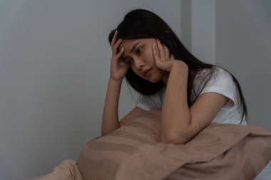 Asyalı kadın geç saatlere kadar uyumaya çalışıyor uykusuzluk çekiyor, uykusuzluk çekiyor ya da bir kabusta korkuyor üzgün endişeli ve stresli görünüyor. Yorgun ve baş ağrısı ya da gecenin bir yarısı uyanan migren..
