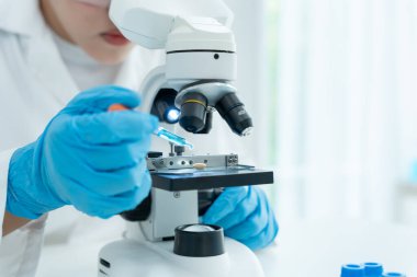 Bilimadamı ileri bilimsel laboratuvarda biyokimyasal örnekleri analiz ediyor. Tıbbi profesyonel kullanım mikroskobu virüsün mikrobiyolojik gelişimini gösteriyor. Fen laboratuvarında biyoteknoloji araştırması