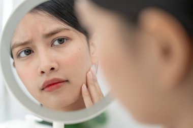 Genç Asyalı kadın, yüz dermatolojisi ve kozmetik ürünlerinde steroidlere alerjisi olduğu için endişeli. Hassas cilt, güneş yanığı, sivilce, kimyasallara alerjisi, yüzünde kızarıklık. cilt sorunları ve güzellik