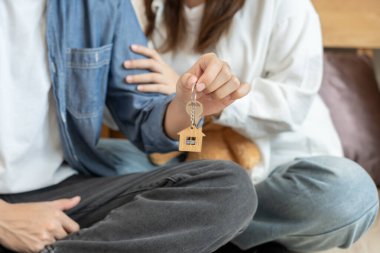Moving house, relocation. Couple hold key house keychain in new apartment, inside the room was a cardboard box containing personal belongings and furniture. move in the new apartment or condominium