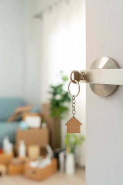 Moving house, relocation. The key was inserted into the door of the new house, inside the room was a cardboard box containing personal belongings and furniture. move in the apartment or condominiu