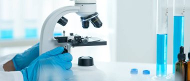 Bilimadamı ileri bilimsel laboratuvarda biyokimyasal örnekleri analiz ediyor. Tıbbi profesyonel kullanım mikroskobu virüsün mikrobiyolojik gelişimini gösteriyor. Fen laboratuvarında biyoteknoloji araştırması