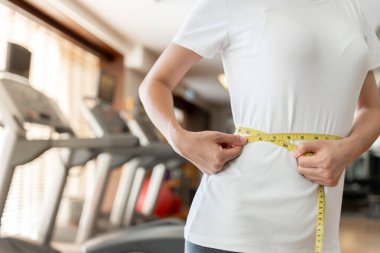 Diyet ve diyet. Güzel, ince kadın vücut ölçüsü fitness için şerit kullanır. Spor elbiseli bir kadın sağlıklı yaşam için kilo verme hedefine, zayıflığa, ince belliye, beslenme uzmanına ulaşır..