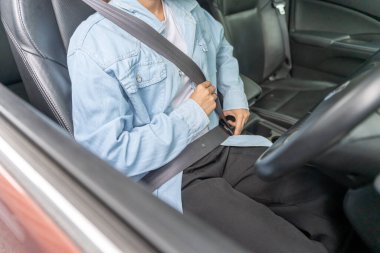 Kadın emniyet kemerini takar ve güvenli sürüş, sürüş antrenmanı yapar. Neşeli kadın sürücü koltuğunda rahatça oturur. Elleri güvenle, yolculuk için hazır.