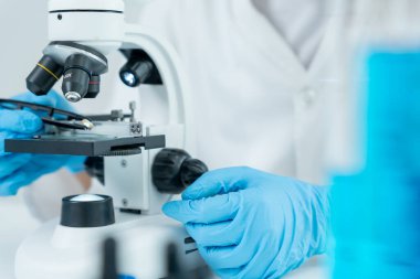 Bilimadamı ileri bilimsel laboratuvarda biyokimyasal örnekleri analiz ediyor. Tıbbi profesyonel kullanım mikroskobu virüsün mikrobiyolojik gelişimini gösteriyor. Fen laboratuvarında biyoteknoloji araştırması.