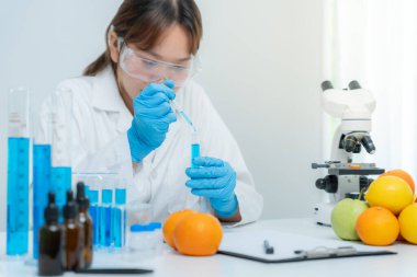 Bilimadamı laboratuardaki kimyasal meyve artıklarını kontrol ediyor. Kontrol uzmanları kimyasal kalıntıların konsantrasyonunu inceliyor. Tehlike, standart, yasaklı maddeleri bul, kirlet, mikrobiyolog