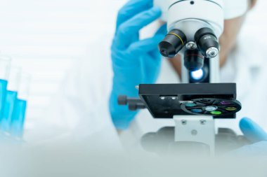 Bilimadamı ileri bilimsel laboratuvarda biyokimyasal örnekleri analiz ediyor. Tıbbi profesyonel kullanım mikroskobu virüsün mikrobiyolojik gelişimini gösteriyor. Fen laboratuvarında biyoteknoloji araştırması