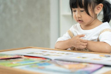 Mutlu Asyalı çocuklar evde kitap okuyarak rahatlar. Kızım ve bir hikaye okuyordum. öğrenme, çocuk bakımı, gülme, eğitim, hikaye anlatma, uygulama, hayal etme, bağımlılık cep telefonunu azaltma