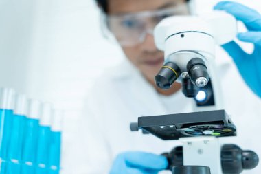 Bilimadamı ileri bilimsel laboratuvarda biyokimyasal örnekleri analiz ediyor. Tıbbi profesyonel kullanım mikroskobu virüsün mikrobiyolojik gelişimini gösteriyor. Fen laboratuvarında biyoteknoloji araştırması