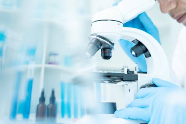 Bilimadamı ileri bilimsel laboratuvarda biyokimyasal örnekleri analiz ediyor. Tıbbi profesyonel kullanım mikroskobu virüsün mikrobiyolojik gelişimini gösteriyor. Fen laboratuvarında biyoteknoloji araştırması.