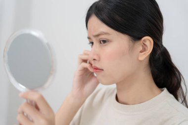 Genç Asyalı kadın, yüz dermatolojisi ve kozmetik ürünlerinde steroidlere alerjisi olduğu için endişeli. Hassas cilt, güneş yanığı, sivilce, kimyasallara alerjisi, yüzünde kızarıklık. cilt sorunları ve güzellik