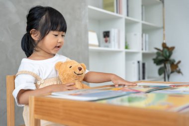 Mutlu Asyalı çocuklar rahatlayın ayı bebek için masal kitabı okuyun. Kızım ve bir hikaye okuyordum. öğrenim geliştirme, çocuk bakımı, eğitim, hikaye anlatma, uygulama, hayal etme, bağımlılığı azaltma cep telefonu