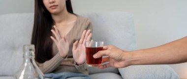 Kadın hayır demeyi reddediyor ve alkol içmekten kaçınıyor, el işaretini durduran kadın, alkolizm tedavisi, alkol bağımlılığı, içkiyi bırakmak, alkol içmeyi bırakmak. İçkiyi reddet, sağlıksız.