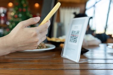 Woman use smartphone to scan QR code to pay in cafe restaurant with a digital payment without cash. Choose menu and order accumulate discount. E wallet, technology, pay online, credit card, bank app.