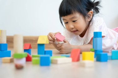 Mutlu Asyalı çocuk oyun oynuyor ve oyuncak bloklarını öğreniyor. Çocuklar evde çok mutlu ve heyecanlı. Çocuk oyun, etkinlik, gelişme ve dikkat eksikliği hiperaktivite bozukluğuyla çok iyi vakit geçiriyor