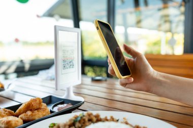Woman use smartphone to scan QR code to pay in cafe restaurant with a digital payment without cash. Choose menu and order accumulate discount. E wallet, technology, pay online, credit card, bank app.