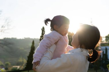 Anne kucaklıyor ve kızını kucaklıyordu açık havada oynuyordu. Aile çocukluğu gelişimi ve sevgiyle büyümesi annesinin endişelerine destek oluyordu. Mutlu bebeğin hayali.