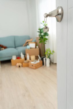 Moving house, relocation. The key was inserted into the door of the new house, inside the room was a cardboard box containing personal belongings and furniture. move in the apartment or condominium