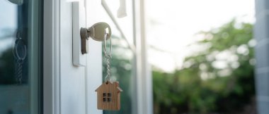 Landlord key for unlocking house is plugged into the door. Second hand house for rent and sale. keychain is blowing in the wind. mortgage for new home, buy, sell, renovate, investment, owner, estate
