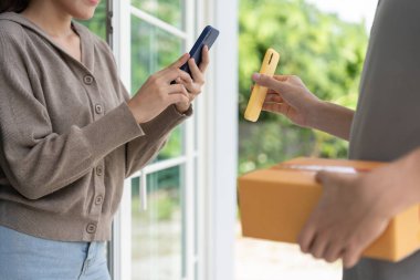 Mutlu Asyalı kadın ödeme için QR kodunu tarıyor. Teslimatçı ekspres teslimat gönderdi. Çevrimiçi dükkan, kağıt konteynır, paket servis, paket, elektronik para, dijital transfer