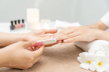 Kadın, güzellik merkezinde profesyonel güzellik manikürü ile bakım hizmeti alıyor. Güzellik salonunda jöle tedavisi için tırnak törpüsü kullanın. Manikürcü, çivi müşterisini güzelleştirir. vücut bakımı spa tedavisi