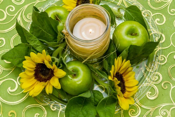 Dish with green apples, flowers and candle — Stock Photo, Image