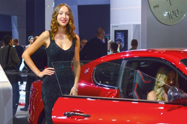 Een jonge vrouw uit het team Maserati. In de lange zwarte jurk in de buurt van auto. Gran Turismo. Rode auto. Moskou internationale Auto Salon Look — Stockfoto