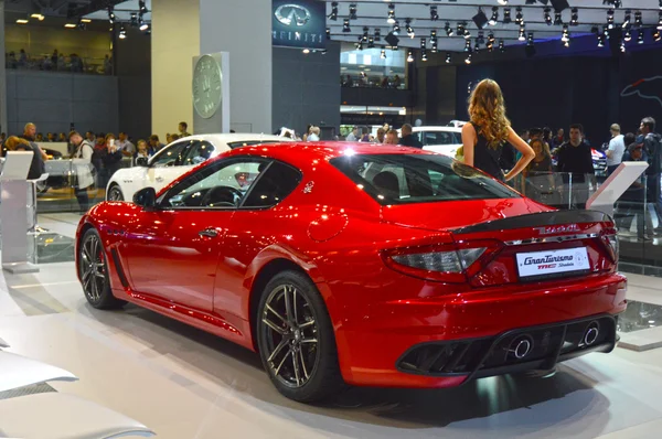 Eine junge Frau aus dem Maserati-Team. im langen schwarzen Kleid in der Nähe des Autos. Gran Turismo. rotes Auto. Moskauer internationaler Automobil-Salon Luxusverkehr — Stockfoto