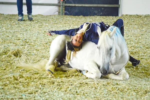 Mostra Lo spettacolare movimento Donna fantino in abito blu ruota su un cavallo bianco. Esposizione internazionale dei cavalli — Foto Stock