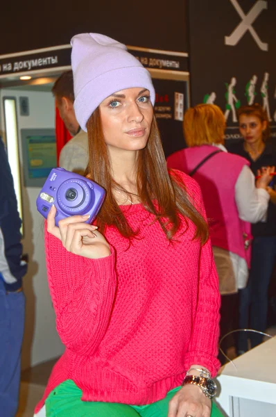 Young female model posing with a digital camera on a stand-known manufacturer of photographic equipment   Photo Expo-2015. Moscow — Stock Photo, Image