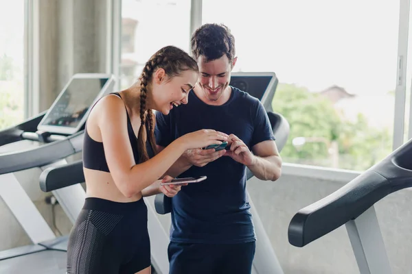 커플들은 체육관에서 운동을 근처에서 스마트폰을 가지고 즐겁게 부부들 — 스톡 사진